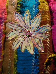 Batik print fabric cut-out and bondawebbed onto the cover. Seed bead details the centre of the flowers